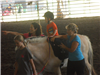 Little Kid riding a horse with women assisting it